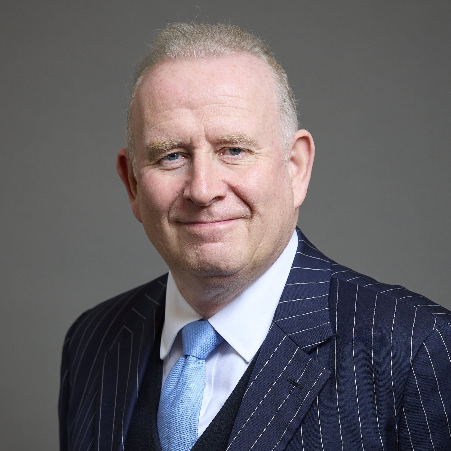 Man in pinstripe suit with blue tie smiling