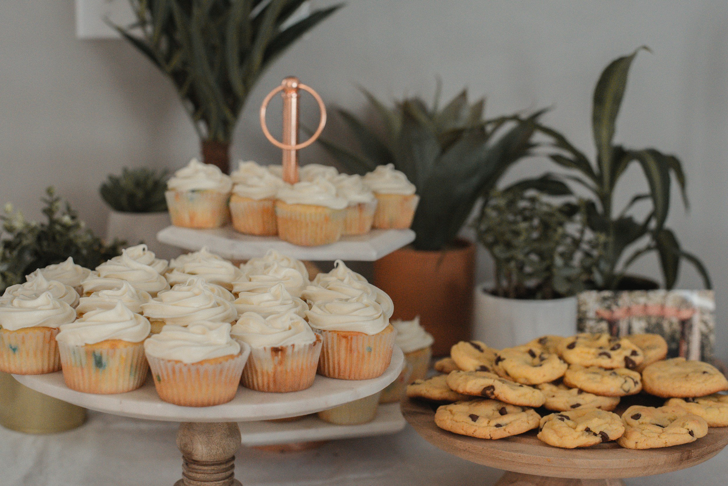 A delightful arrangement of cupcakes and cookies on a table, featuring a decorative cake stand at the centre.