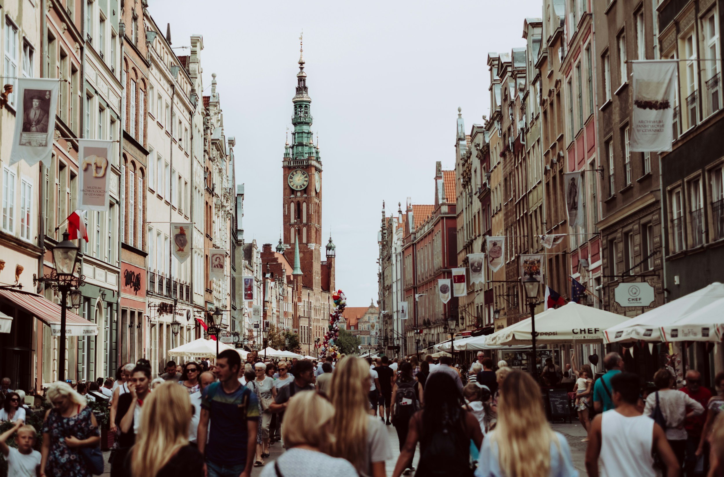A bustling city street in the commercial district, with people walking past shops and restaurants.